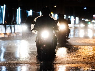 It rains on the city on streets with cars and motorcycles.